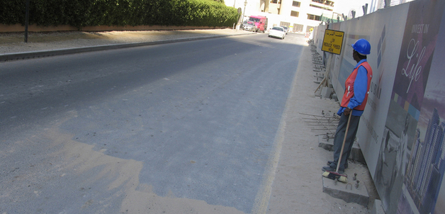 Construction worker cleaning the road, in Dubai - by Paul Keller